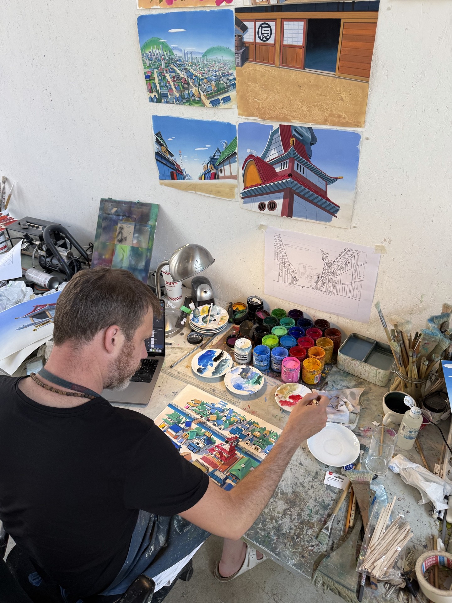 Background art being hand-painted. Finished backgrounds are pinned to the wall