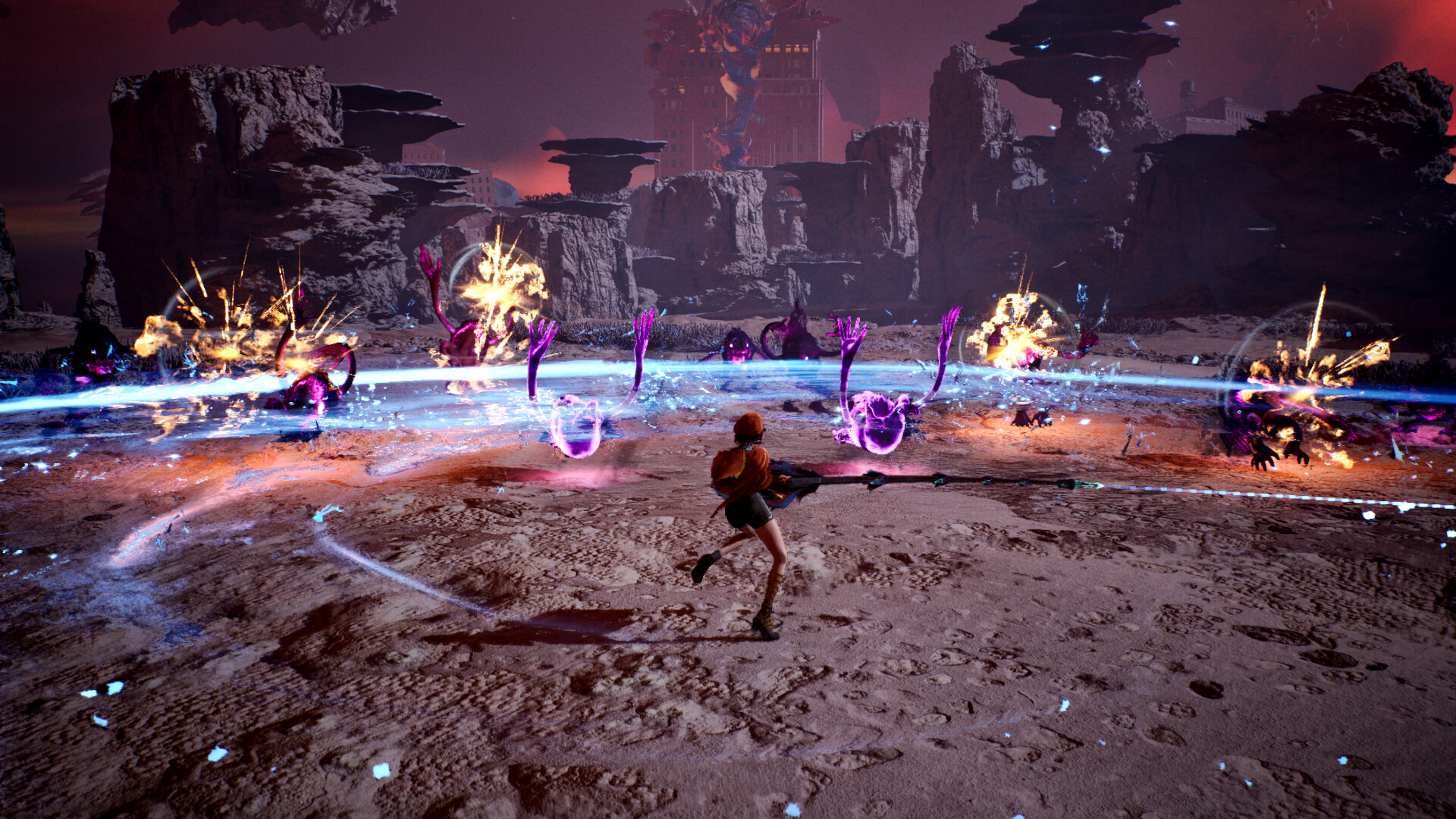 Ellie, seen from behind in a red hood, swings a long staff across a rocky wasteland as an arc of blue light and bursts of fire strike a ring of purple creatures