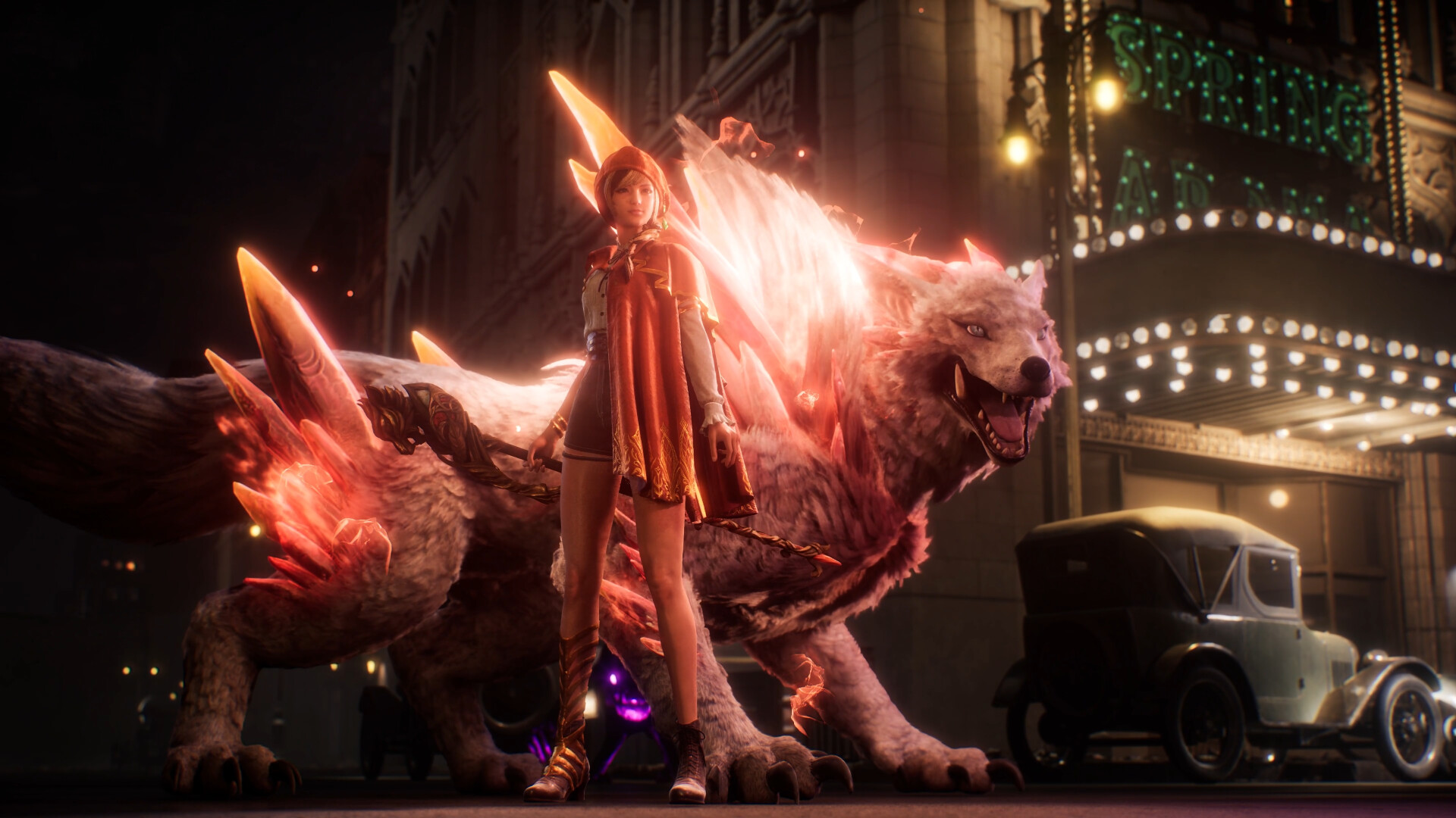 Ellie in a red hooded cape holds a staff in front of a huge wolf covered in glowing orange crystals, on a street at night with a lit theater marquee and a vintage car